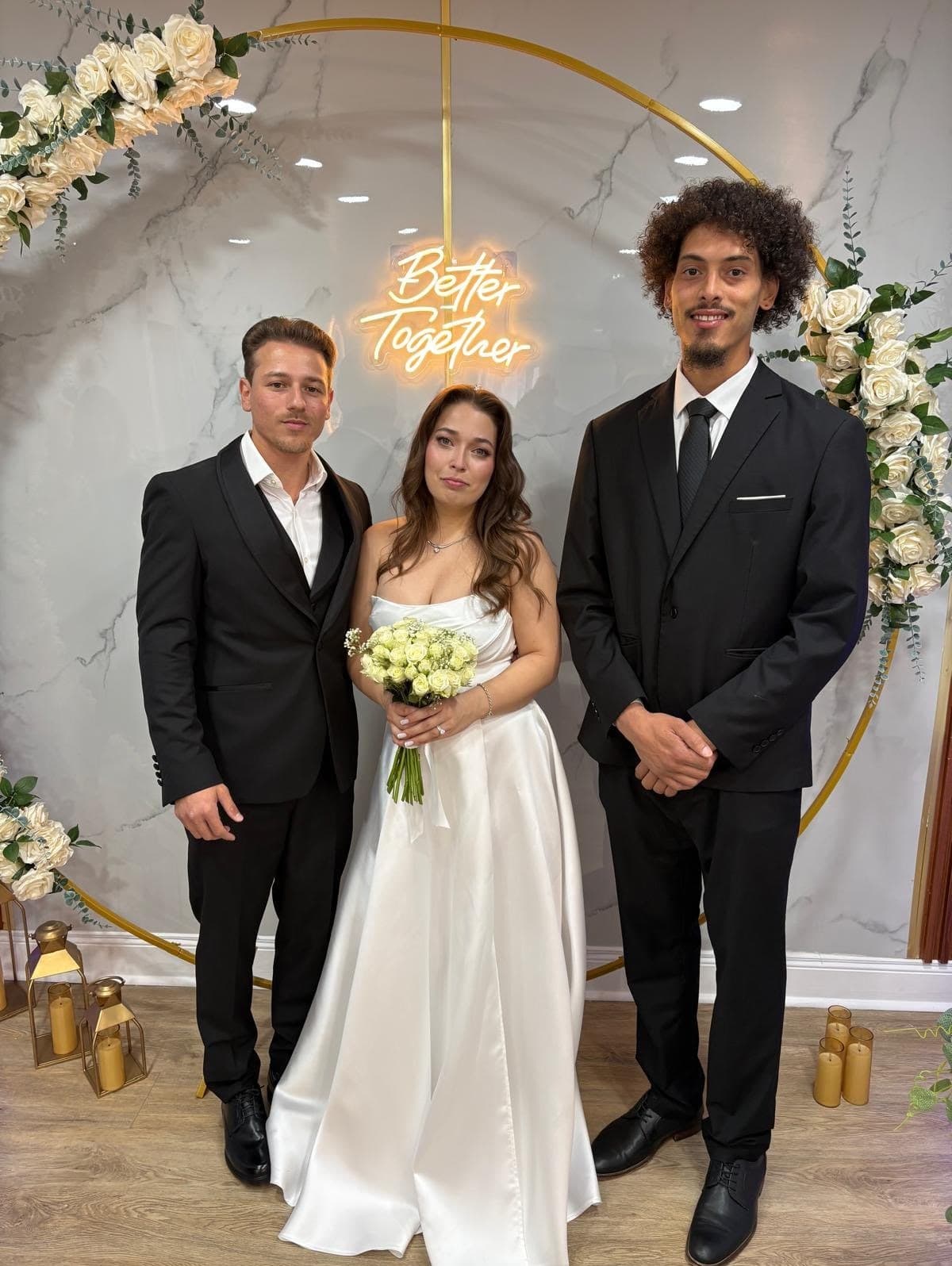 Pareja recién casada con el ministro bajo el arco de flores de The Celebration Room